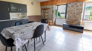 A modern kitchen with a dining table, chairs, and a stone wall.