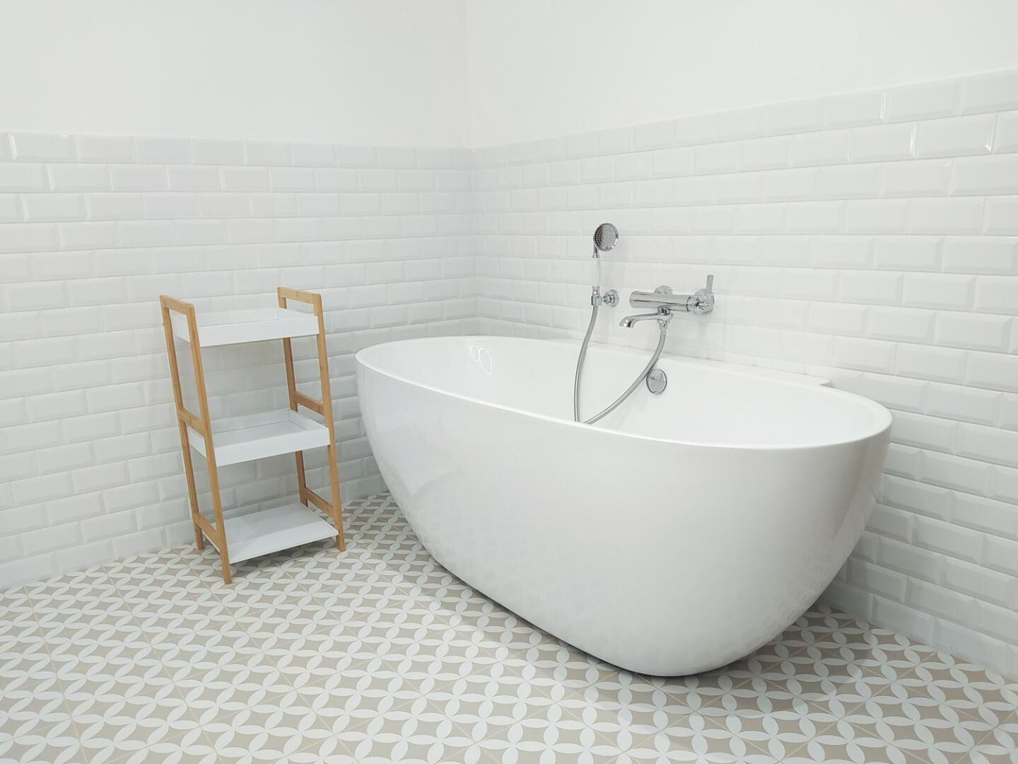 Een moderne badkamer met een vrijstaand bad, een houten wandplank en een vloer met een patroon.