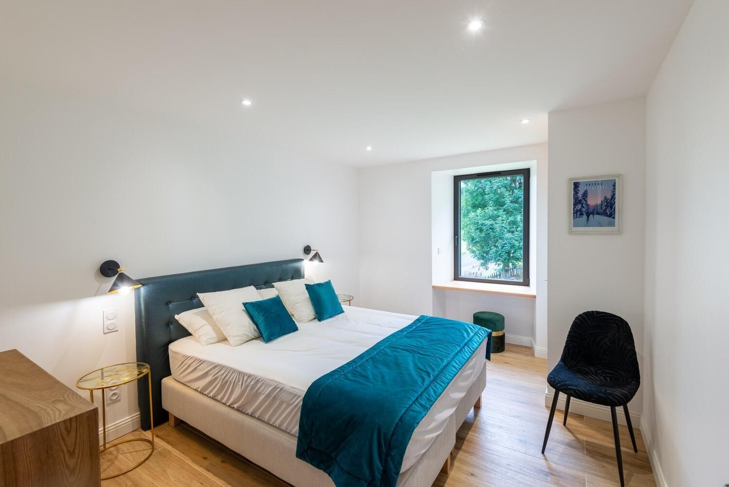 A modern bedroom with a bed, bedside tables, a window with a view, and a chair.