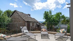 Eine Terrasse mit Liegestühlen und einem Steinhaus im Hintergrund.