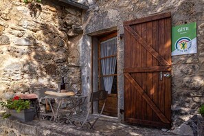 A rustic stone building with a wooden door and a sign for Gîte Lozère.