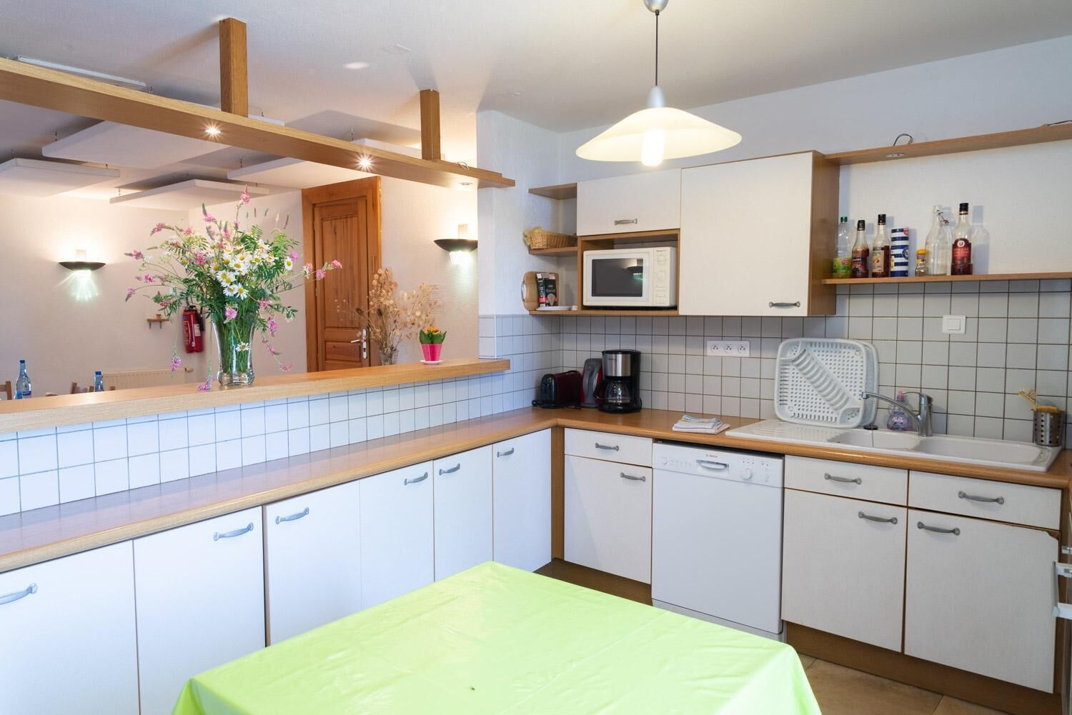A modern kitchen with white cabinets, a wooden countertop, a microwave, a coffee maker, and a sink.