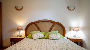 Een slaapkamer met een groot bed, twee nachtkastjes en twee wandlampen.