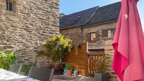 A stone building with a wooden gate, potted plants, and a table with chairs. - L'Oustal de Pagat - LES HERMAUX (LES HERMAUX)