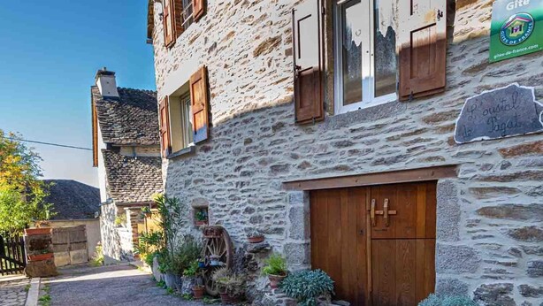 A stone building with wooden shutters, a large wooden door, and a sign indicating 'Gîte de France'. - L'Oustal de Pagat - LES HERMAUX (LES HERMAUX)