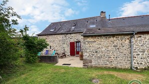 A stone building with a red door, a small porch, and a grassy yard. - Boeuvres-corbinières (GUIPRY MESSAC)