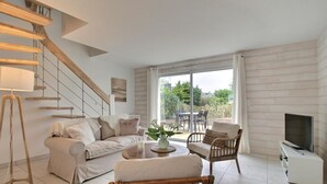 Een moderne woonkamer met een trap, een bank, een salontafel, een fauteuil en een televisie.