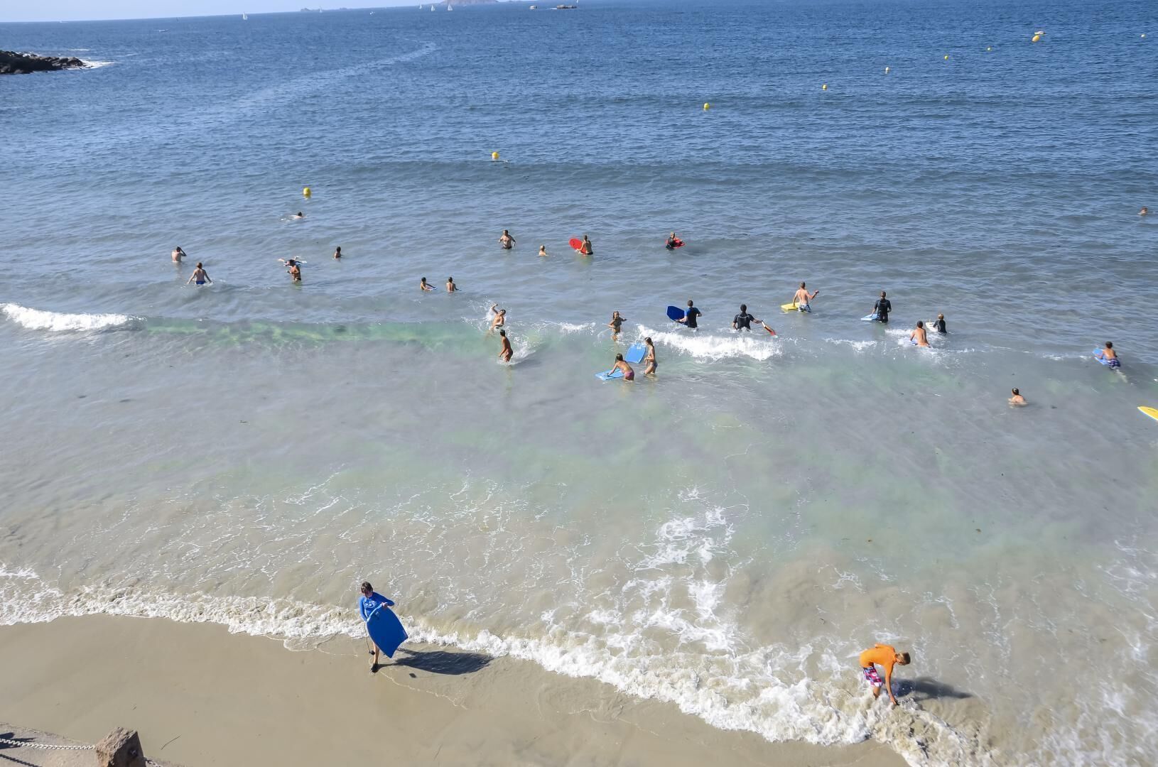 A beach with clear water and people engaging in various water activities.