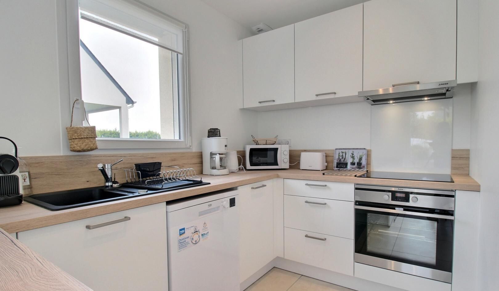A modern kitchen with white cabinets, a built-in dishwasher, a microwave, a toaster, and an oven.