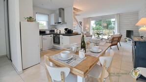 Een moderne keuken met witte kasten, een eethoek met een houten tafel en uitzicht op de omgeving.