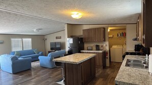 A compact living space with a kitchenette, a dining area, and a seating area with a blue sofa. - Spacious 4BR, 2BA, near Lake, Golf Course, and hot springs! (Elephant Butte)