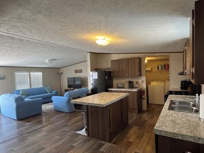 A compact living space with a kitchenette, a dining area, and a seating area with a blue sofa.