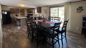 A compact kitchen with a dining area, wooden flooring, and a view through the window. - Spacious 4BR, 2BA, near Lake, Golf Course, and hot springs! (Elephant Butte)