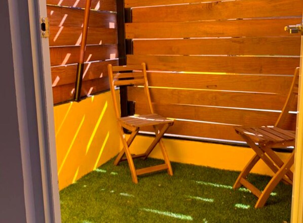Eine Sitzecke mit zwei Holzstühlen, einer Holzwand und Kunstgraseinsatz.