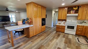 Una cocina amplia con armarios de madera, una isla central y un comedor con televisor y asientos cómodos.