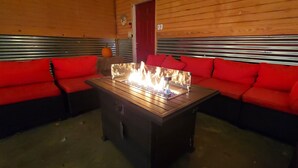 Una habitación acogedora con decoración de madera, un sofá de estructura metálica y una mesa central con chimenea.