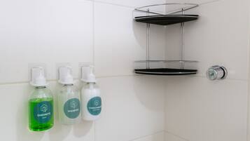 A bathroom with three bottles of soap and a metal shelf unit.