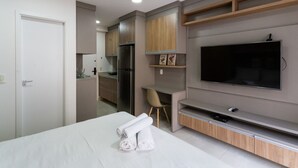 A modern hotel room with a bed, a TV, a desk, and a kitchenette. - Studio Aurora Paulista 606  (São Paulo)