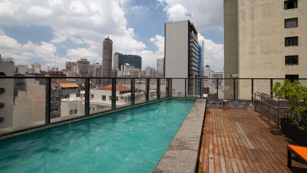 A rooftop pool with a city view, surrounded by buildings and a clear sky. - Studio Aurora Paulista 606  (São Paulo)