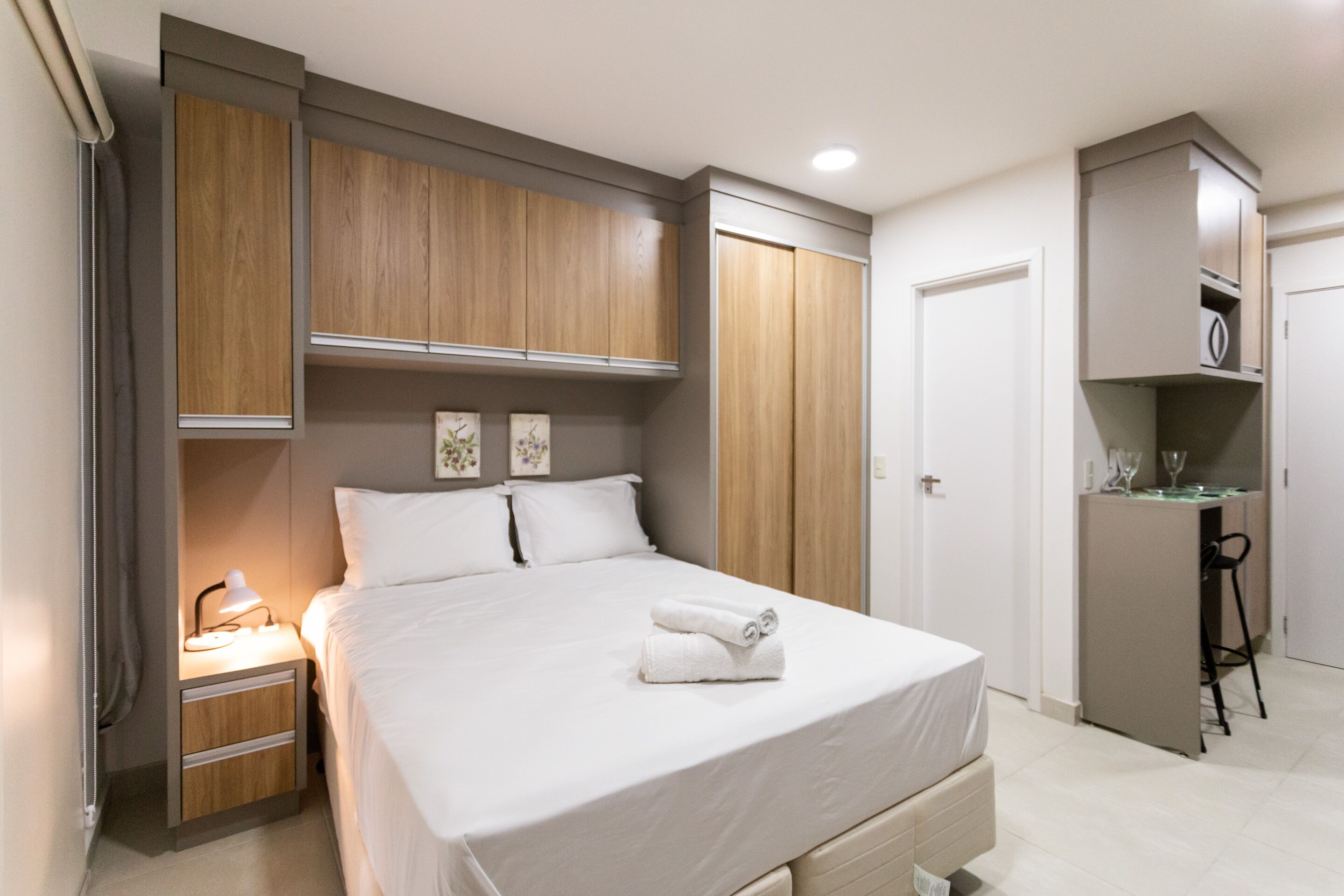 A bedroom with a bed, bedside table, lamp, and wardrobe.