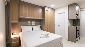 A bedroom with a bed, bedside table, lamp, and wardrobe.