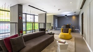 A modern living room with a sofa, a yellow chair, and a coffee table. There is a large window with a view of greenery outside. - Studio Aurora Paulista 606  (São Paulo)