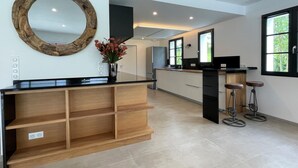 Una cocina moderna con una isla de madera, taburetes de bar y un espejo grande.