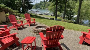 A lakeside patio with red Adirondack chairs and a fire pit. - Lake Chatuge beauty w/private dock, fire pit, pool table, grills and A+ views! (Hayesville)