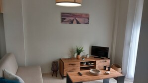 Un salon moderne avec un canapé, une table basse en bois, un téléviseur et un tableau accroché au mur.