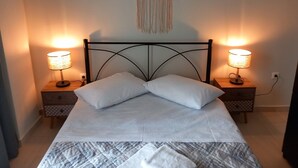 Un lit avec du linge de lit blanc, deux lampes de chevet et une décoration murale en macramé.