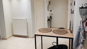Une cuisine moderne avec un radiateur blanc, une table en bois agrémentée de deux sets de table décoratifs et une chaise noire.
