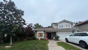 Une maison à deux étages avec un garage, une allée et un panier de basketball.