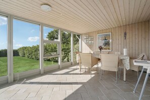 Enjoy a serene view of the surrounding landscape from the large windows in this room, which features a dining area and a comfortable seating space.