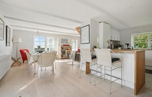 Enjoy a spacious living area with a dining table for four, a bookshelf, and a kitchen with a microwave and coffee machine.