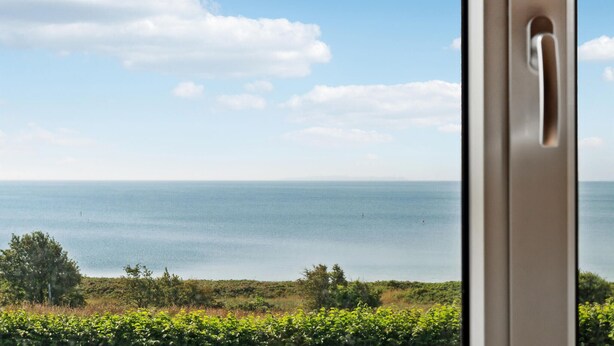 Blick auf das Meer durch ein Fenster mit Türgriff.
