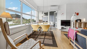 Een moderne woonkamer met een groot raam, een eethoek en een televisie.