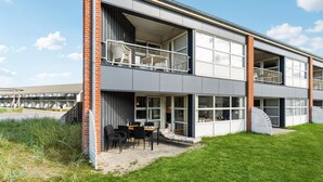 Een modern gebouw met twee verdiepingen, een balkon, grote ramen en een gazon.