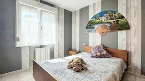 A bedroom with a bed, a window with curtains, a radiator, a nightstand, a clock, and a wall-mounted fan. - Awesome home in Quoux-Haut-Maînil with WiFi (Quoux-Haut-Maînil)