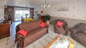 A living room with a brown sofa, two armchairs, a coffee table, and a dining area with a yellow tablecloth. - Awesome home in Quoux-Haut-Maînil with WiFi (Quoux-Haut-Maînil)