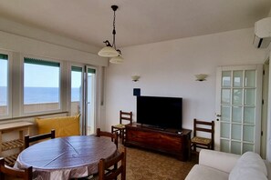 A living room with a round table, chairs, a television, and a sofa.