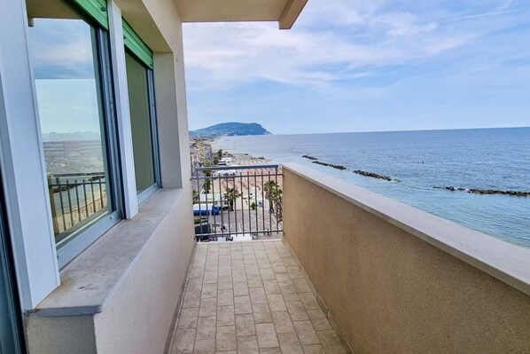 A balcony with a view of the sea and a distant island.