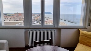 A room with a view of a beach and buildings, a radiator, a bed, and a yellow pillow. - P012 - Porto Recanati, wonderful three-room apartment facing the sea (Porto Recanati)