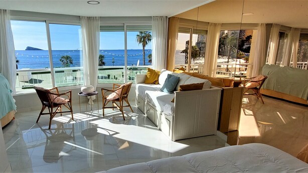 Habitación de hotel con balcón, cama, zona de estar y vista al mar.