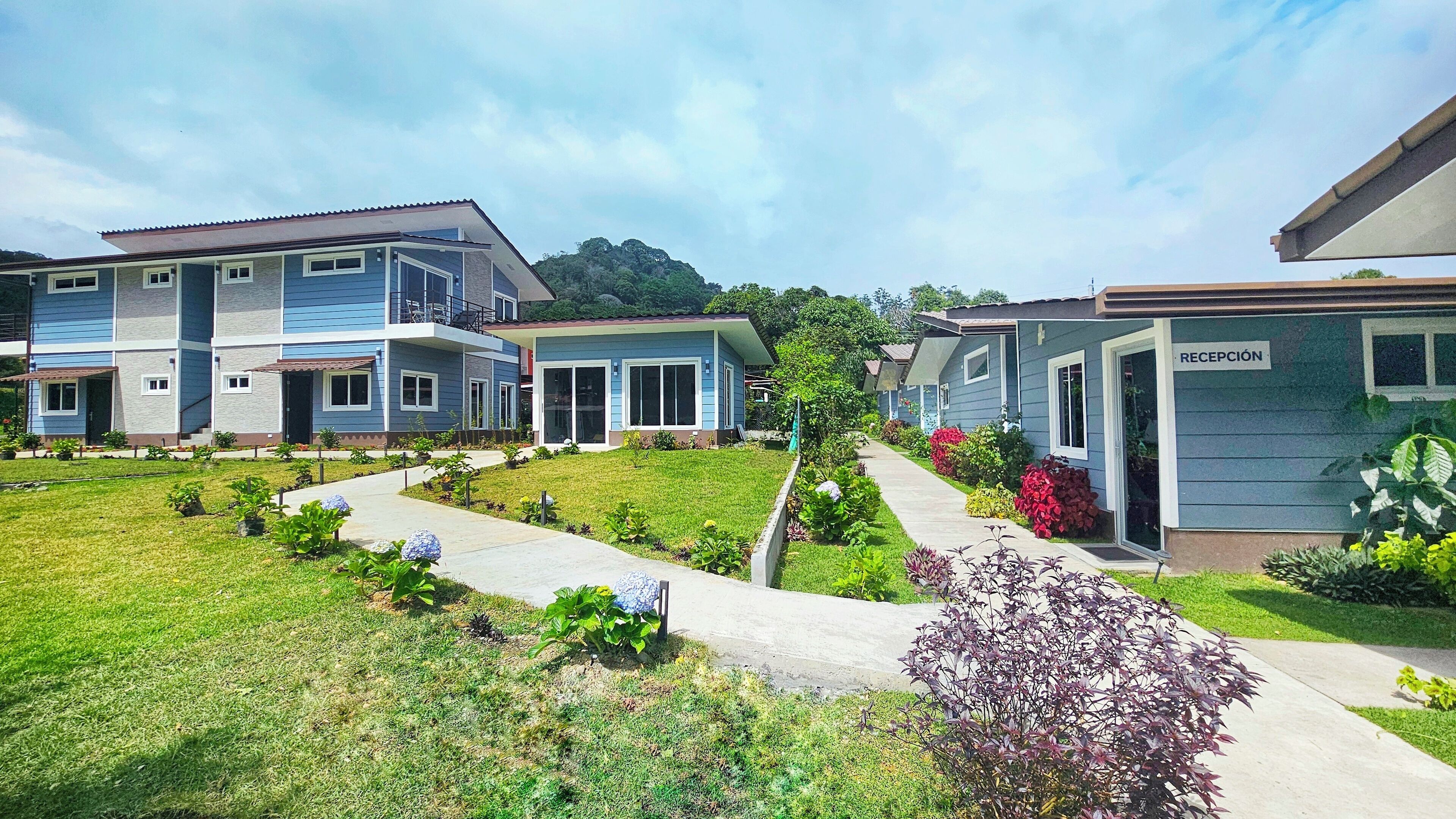 Uma fileira de casas modernas, com dois andares, gramado e jardim bem cuidados.