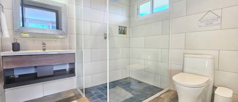 Un baño moderno con cabina de ducha de vidrio, inodoro y tocador con espejo.