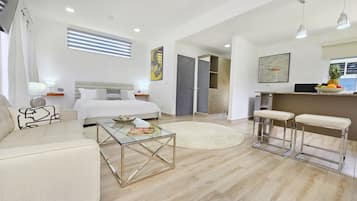 A modern, well-lit bedroom with a large bed, bedside tables, and a glass coffee table.