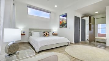 A modern bedroom with a large bed, a window, a painting, and a wardrobe.