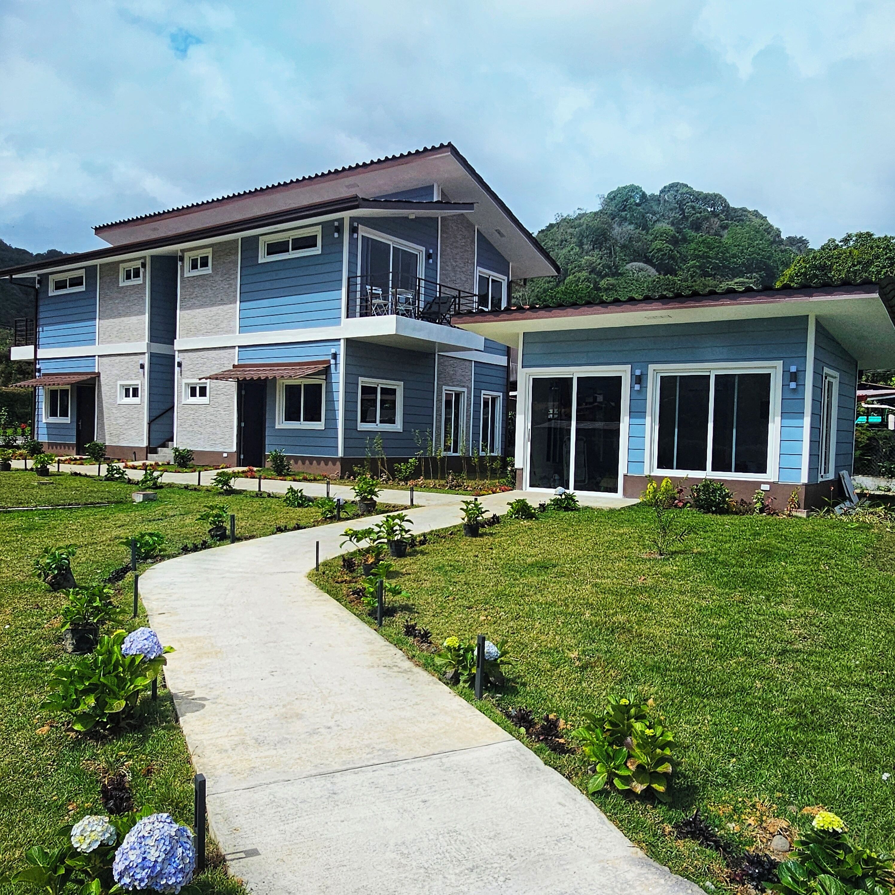 Ein zweistöckiges Haus mit überdachter Terrasse und Gartenweg.