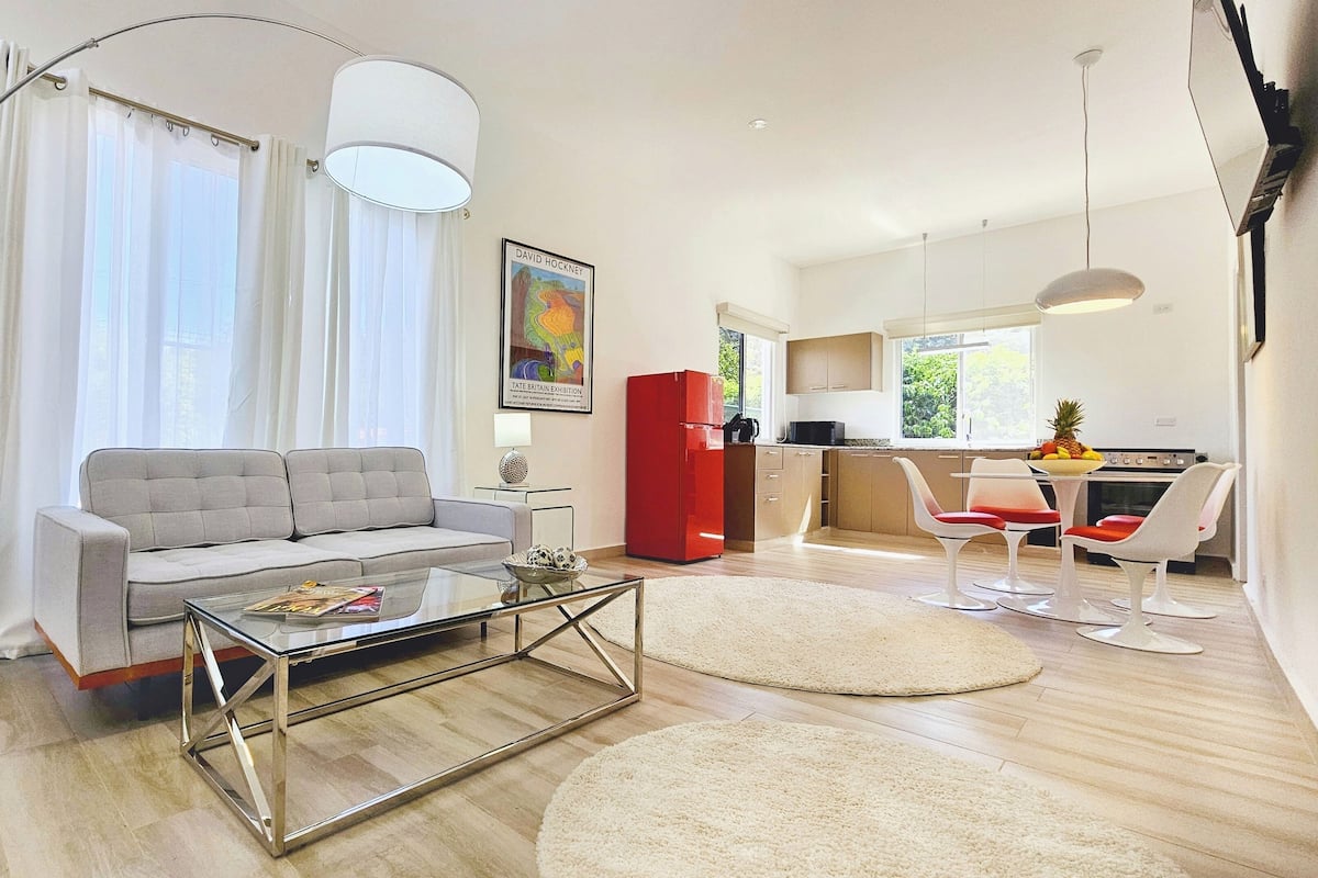 A modern living room with a grey sofa, a glass coffee table, and a red cabinet.