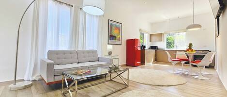 A modern living room with a grey sofa, a glass coffee table, and a red cabinet.